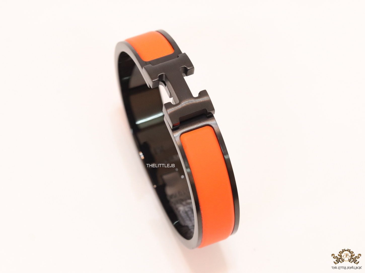 Premium collection band style bracelet in matt orange with black metallic details and black T alphabet motif