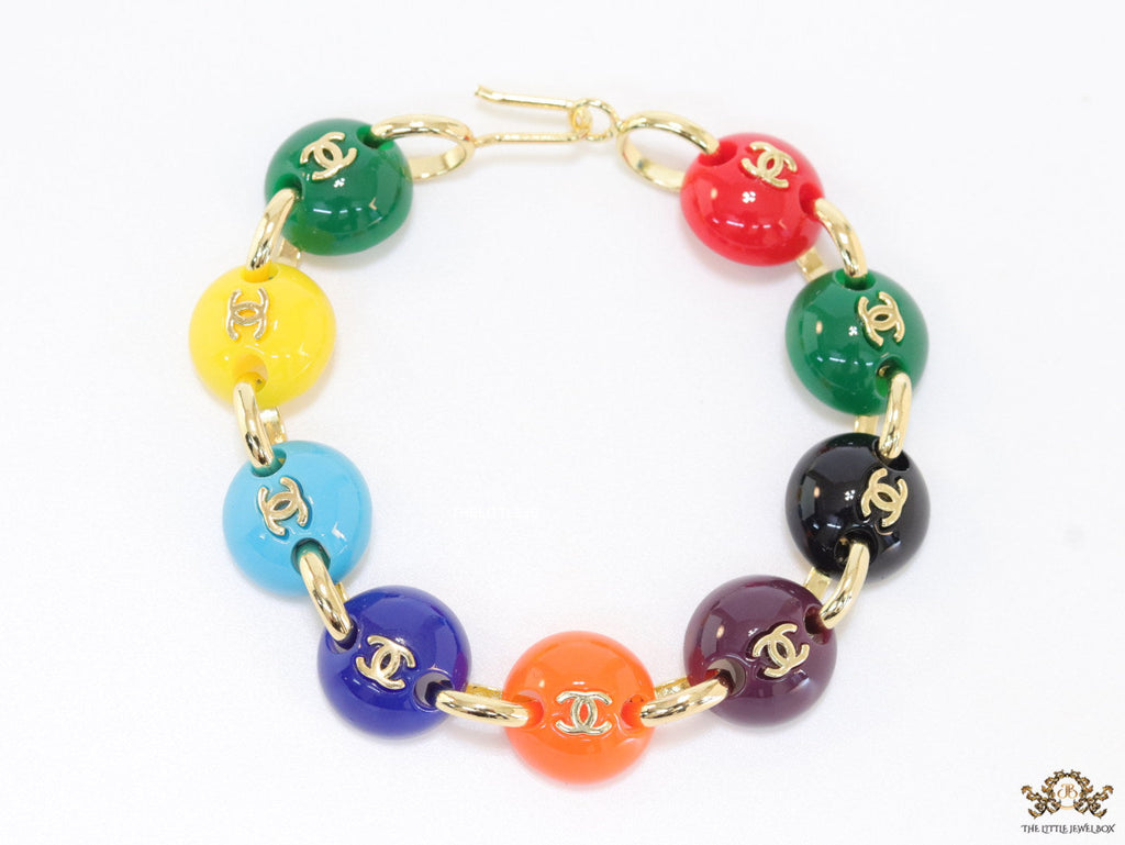 Gold plated link chain bracelet with multi coloured acrylic buttons with gold plated twin C alphabet