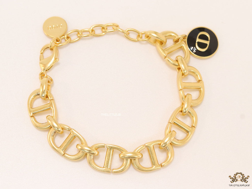 Gold plated link chain bracelet with charms, trinkets and black enamel charm with alphabets