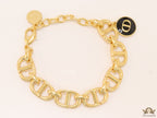 Gold plated link chain bracelet with charms, trinkets and black enamel charm with alphabets