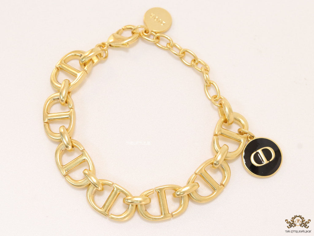 Gold plated link chain bracelet with charms, trinkets and black enamel charm with alphabets
