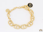 Gold plated link chain bracelet with charms, trinkets and black enamel charm with alphabets