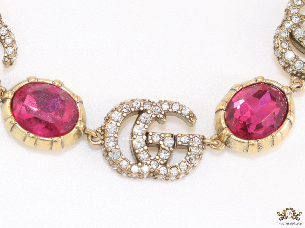 Gold plated linked chain bracelet with gold plated cubic zirconia stones twin G alphabet motifs and gold plated pink cubic zirconia stones