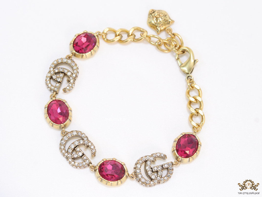 Gold plated linked chain bracelet with gold plated cubic zirconia stones twin G alphabet motifs and gold plated pink cubic zirconia stones