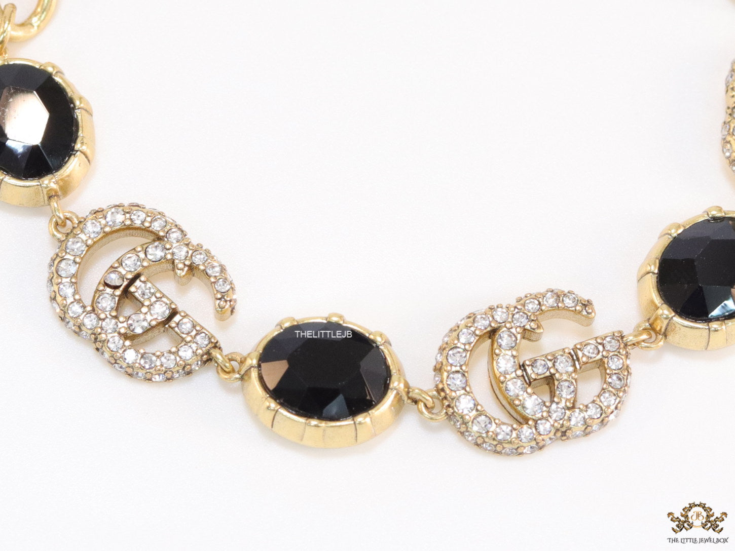 Gold plated linked chain bracelet with black stones and twin G alphabet motif