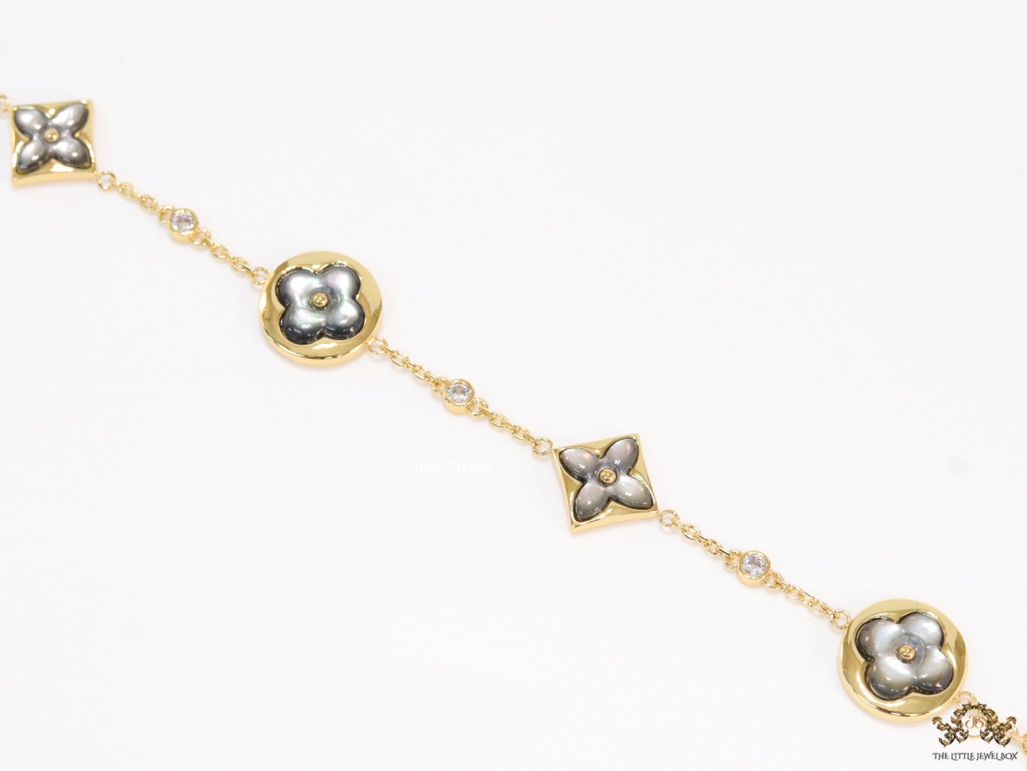 Sleek gold plated chain style bracelet with gold plated grey mother of pearl flower designs