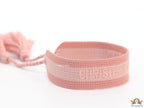 Adjustable pastel pink woven bracelet with knitted alphabets and tassels