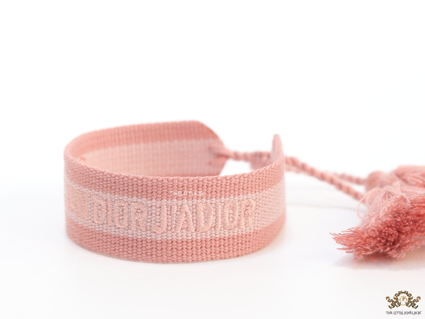 Adjustable pastel pink woven bracelet with knitted alphabets and tassels