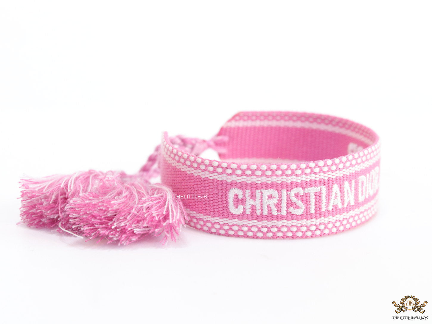 Adjustable pink woven bracelet with white knitted alphabets and tassels
