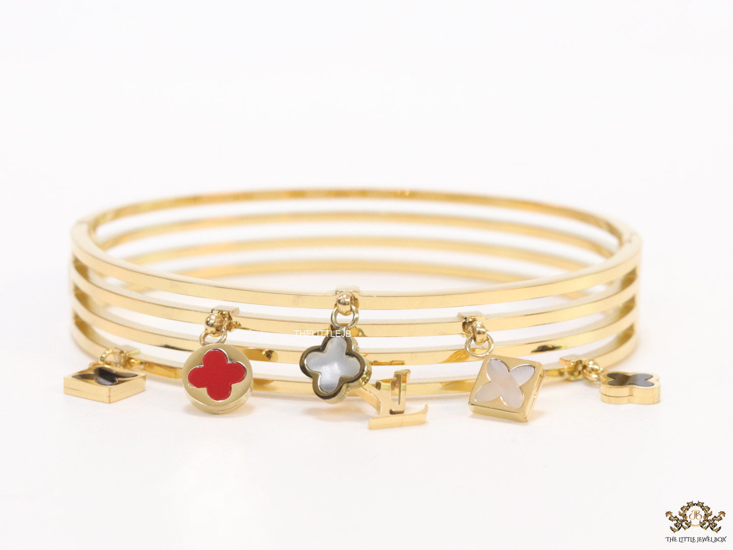 Multilayered golden bracelet with alphabets and coloured clover charms