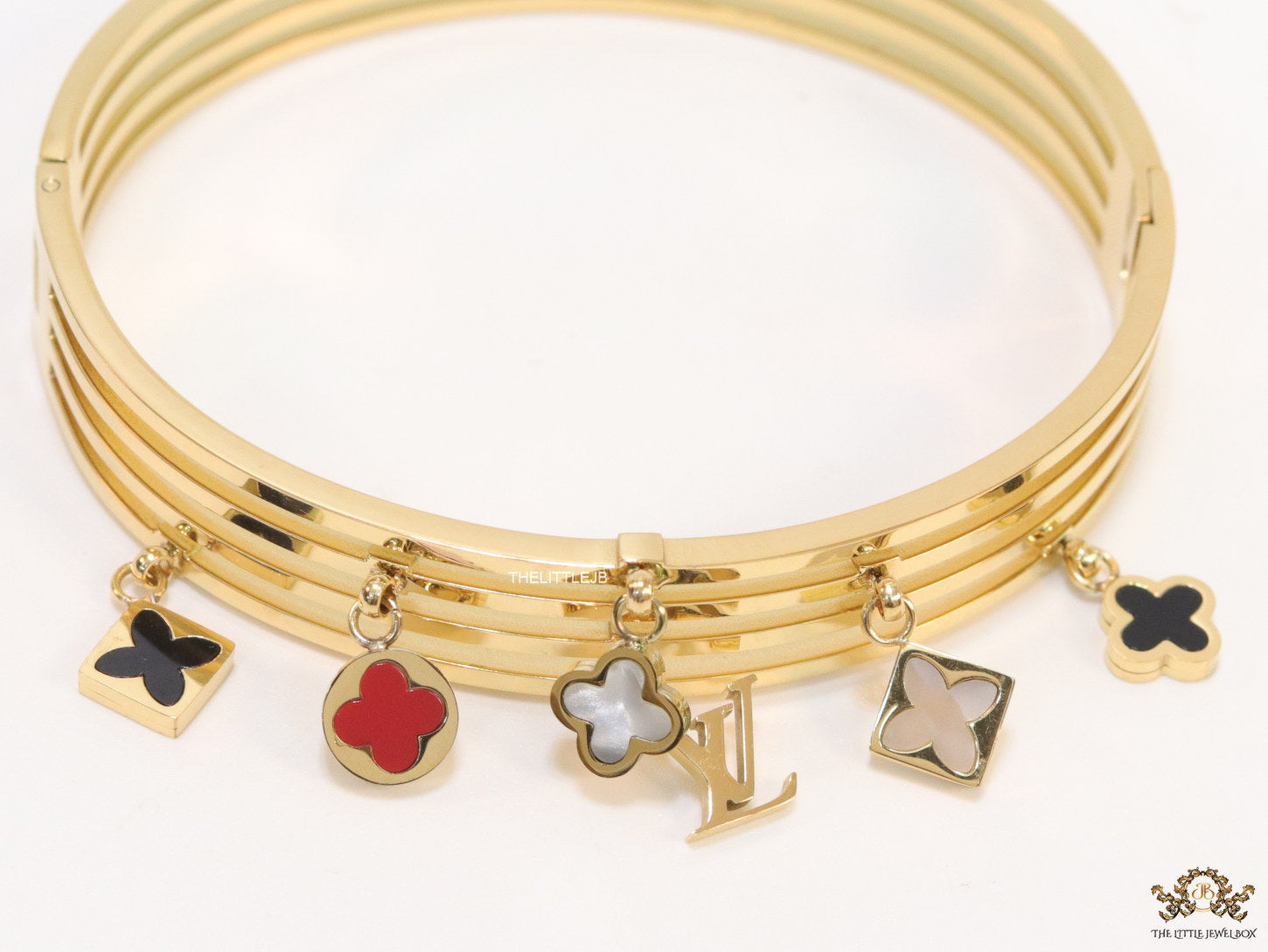 Multilayered golden bracelet with alphabets and coloured clover charms