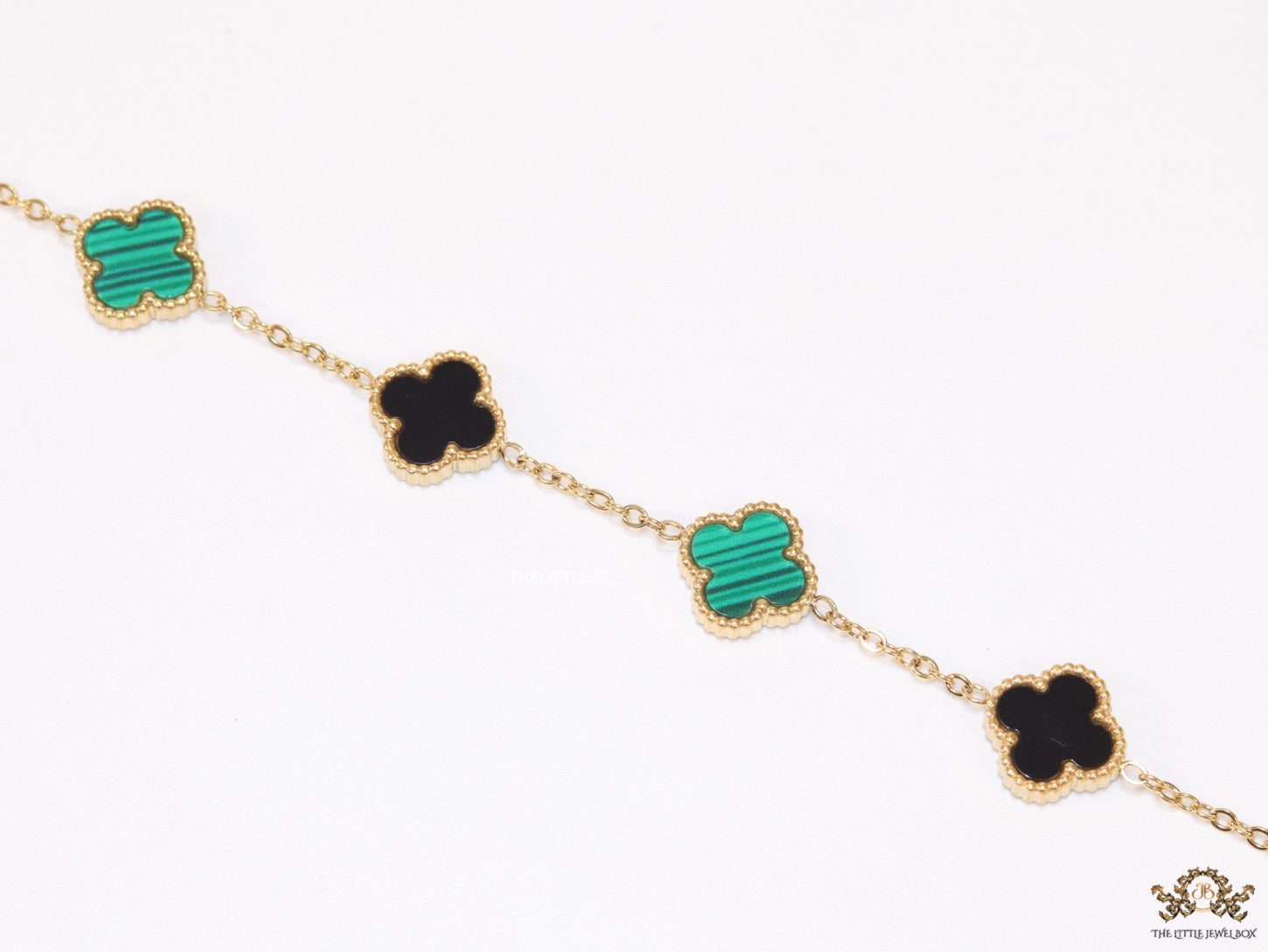 Golden chain bracelet with black and green clovers
