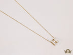 Gold chain necklace with white enamel H motif