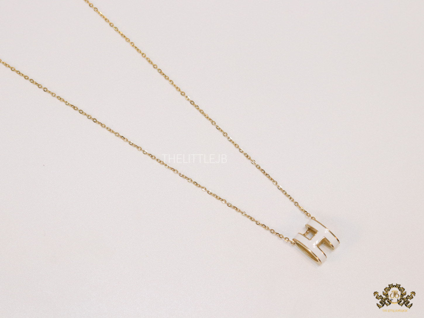 Gold chain necklace with white enamel H motif