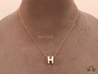 Gold chain necklace with white enamel H motif