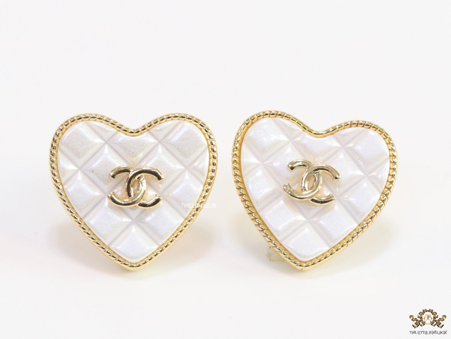 White textured heart shaped studs with twin C motif in golden finish
