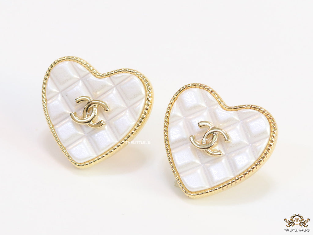 White textured heart shaped studs with twin C motif in golden finish