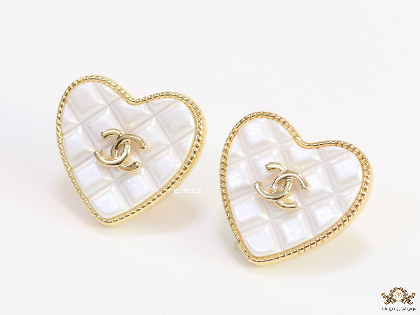 White textured heart shaped studs with twin C motif in golden finish