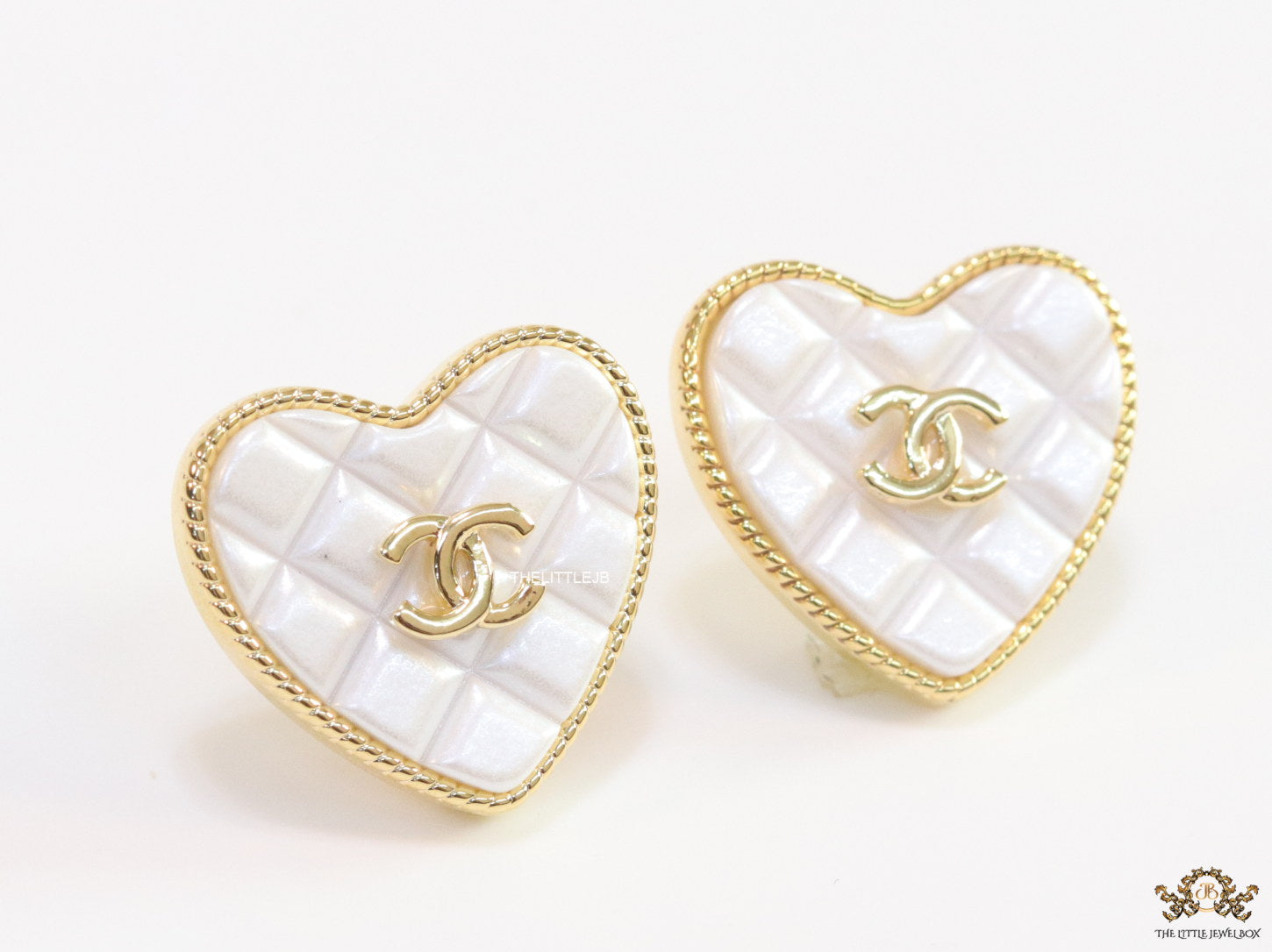 White textured heart shaped studs with twin C motif in golden finish