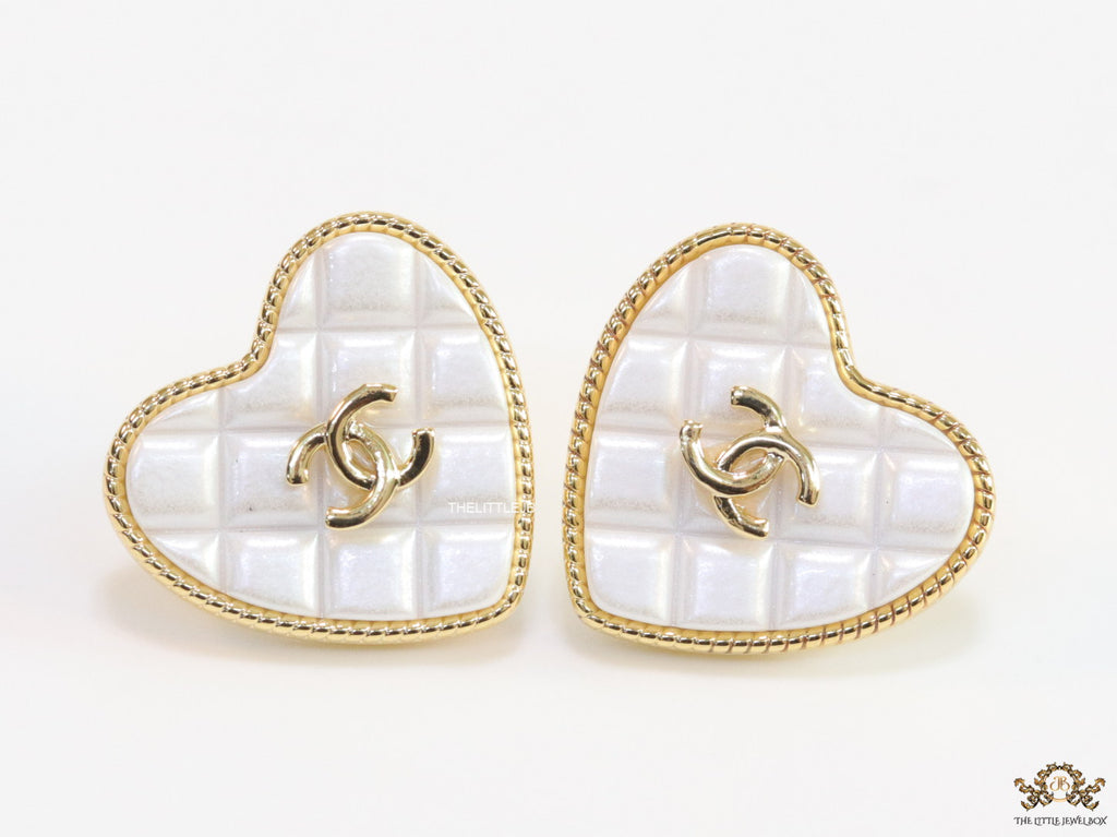 White textured heart shaped studs with twin C motif in golden finish