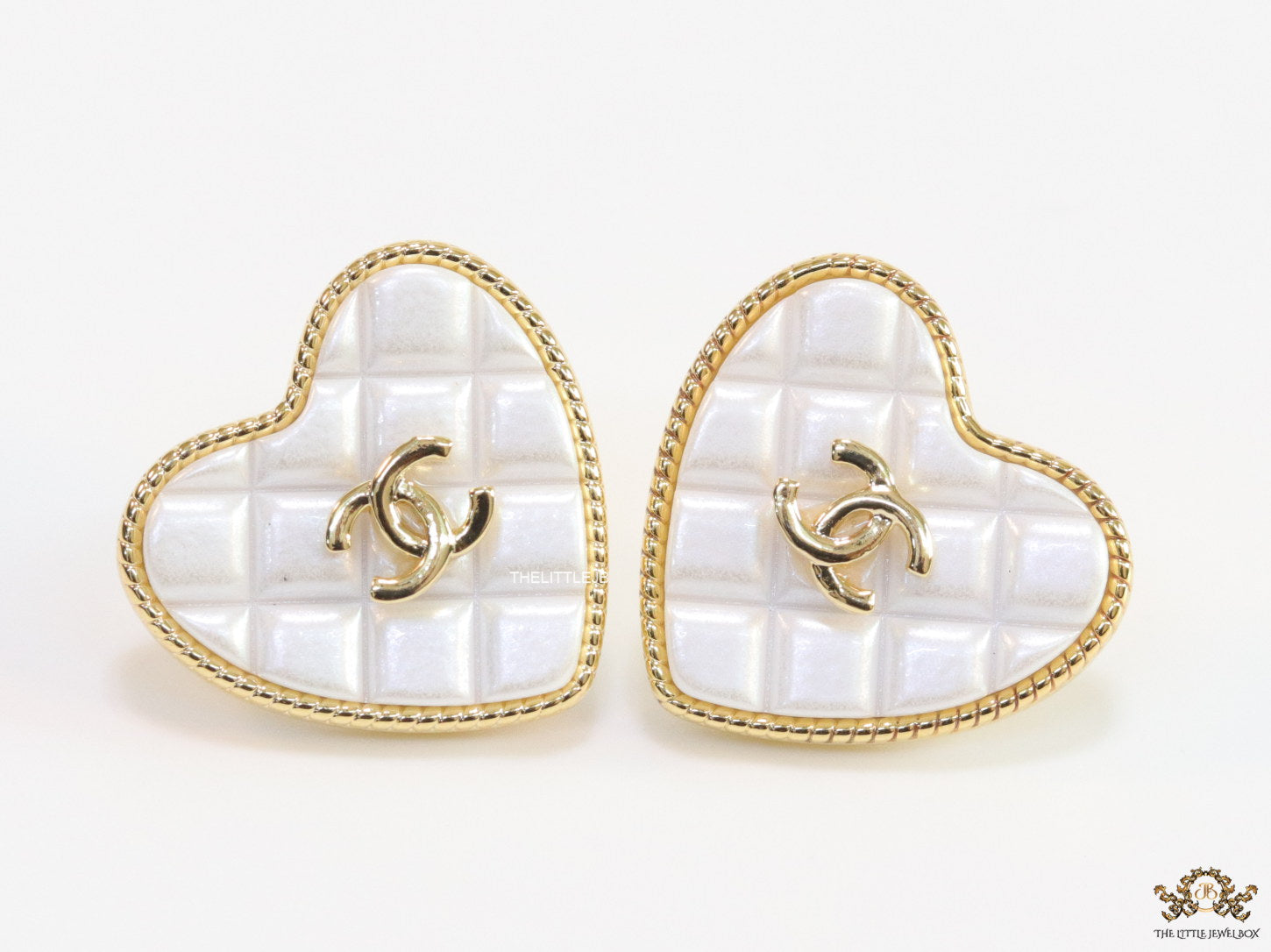 White textured heart shaped studs with twin C motif in golden finish