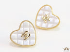 White textured heart shaped studs with twin C motif in golden finish