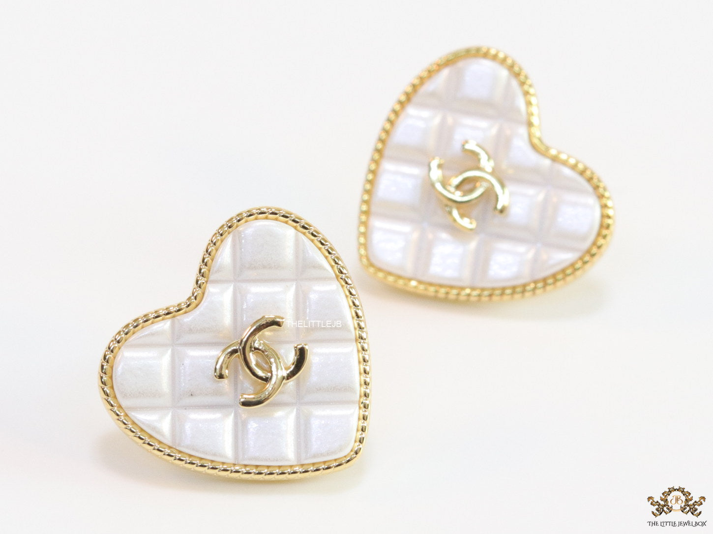 White textured heart shaped studs with twin C motif in golden finish