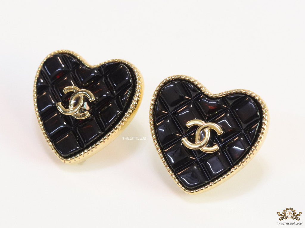 Black textured heart shaped studs with twin C motif in golden finish