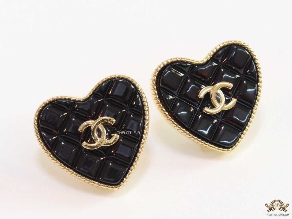 Black textured heart shaped studs with twin C motif in golden finish