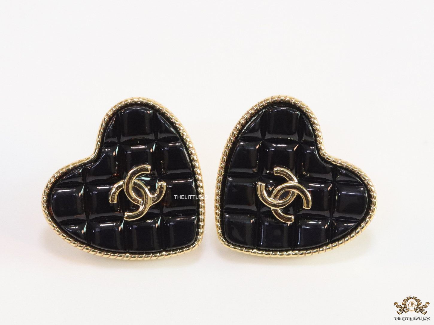Black textured heart shaped studs with twin C motif in golden finish
