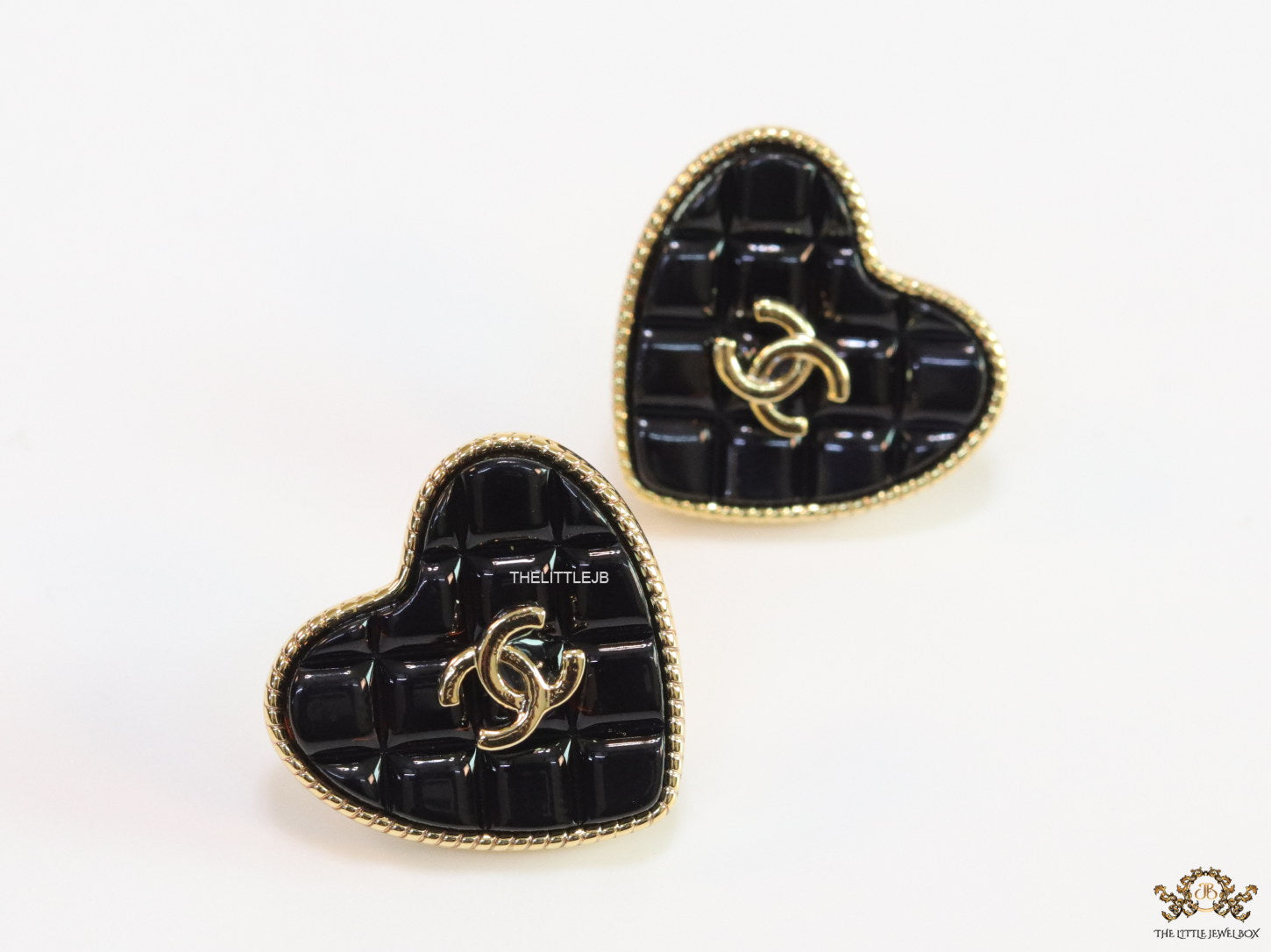 Black textured heart shaped studs with twin C motif in golden finish