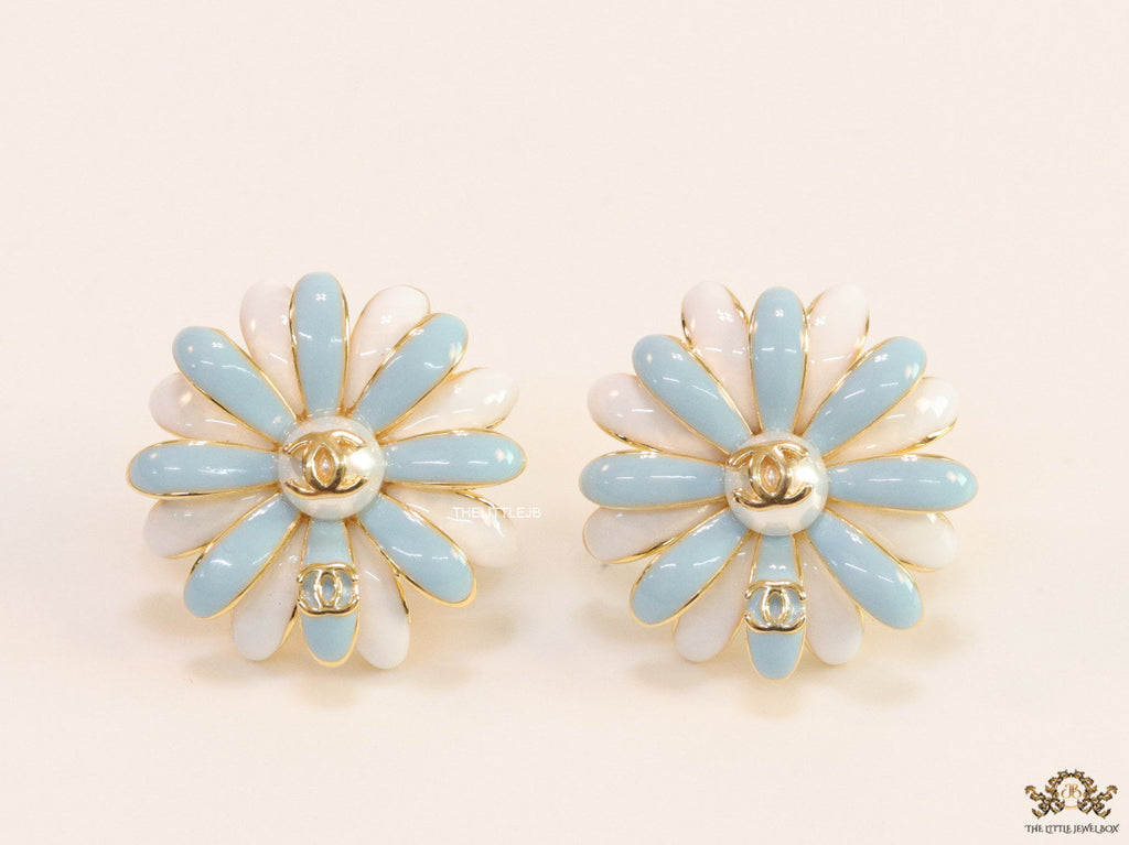 Off-white and soft blue daisy studs with golden details twin alphabet double C motif.