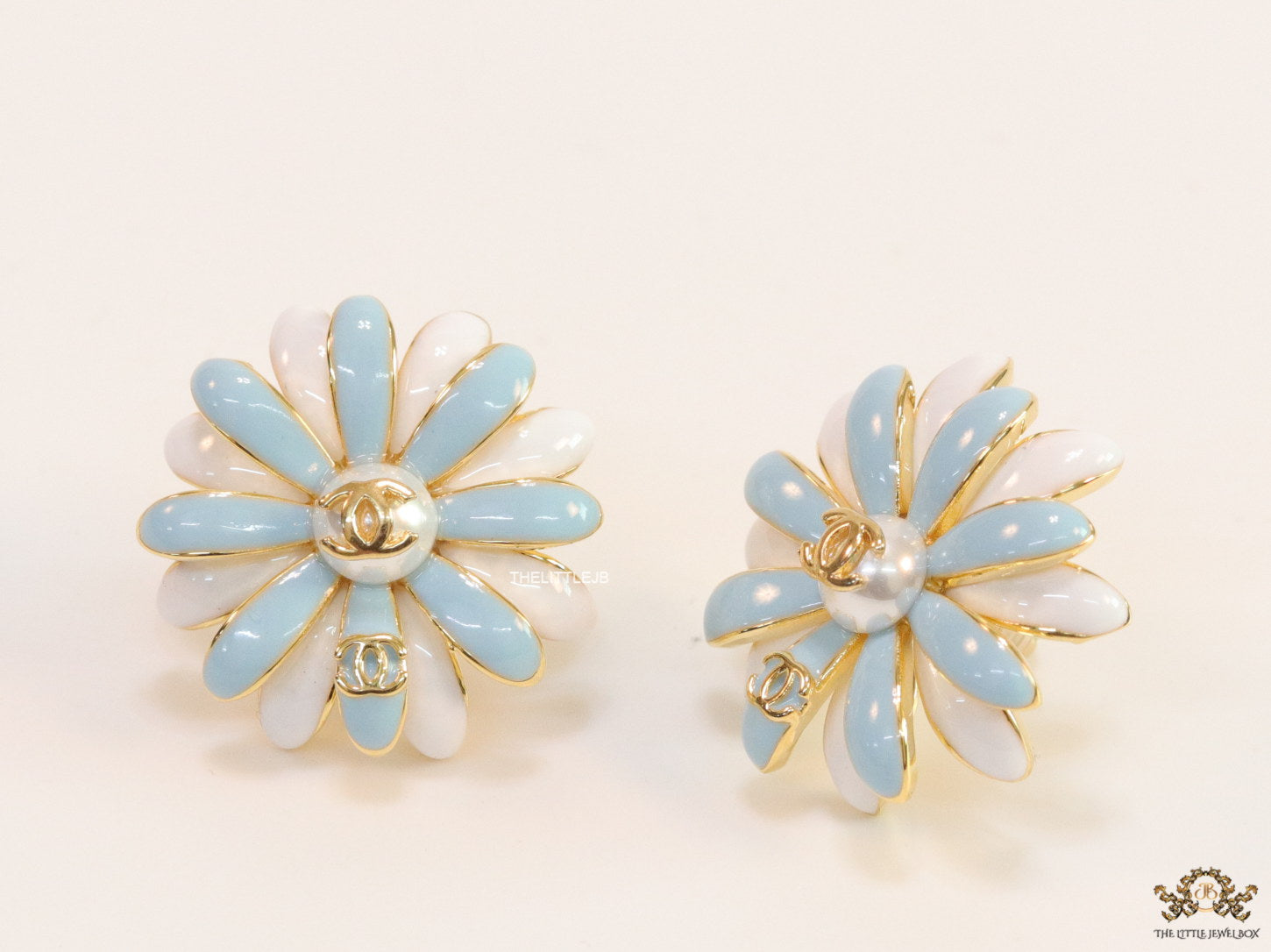 Off-white and soft blue daisy studs with golden details twin alphabet double C motif.
