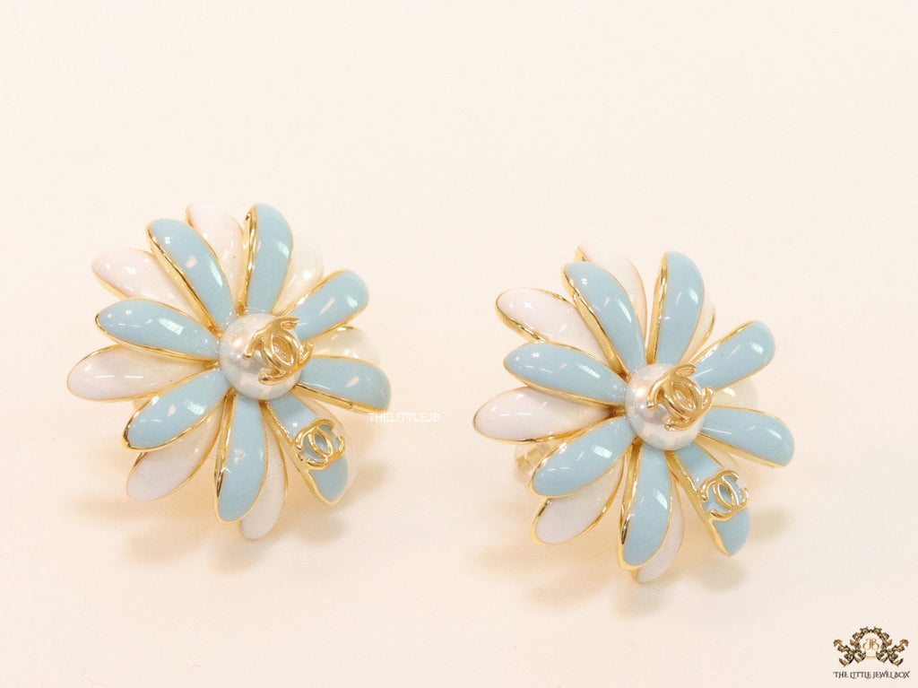 Off-white and soft blue daisy studs with golden details twin alphabet double C motif.