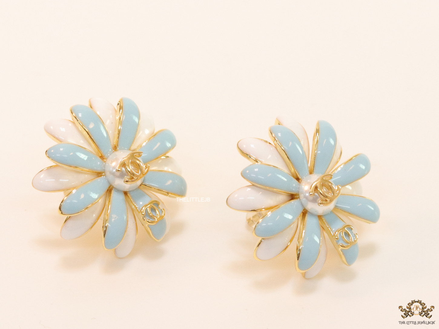 Off-white and soft blue daisy studs with golden details twin alphabet double C motif.