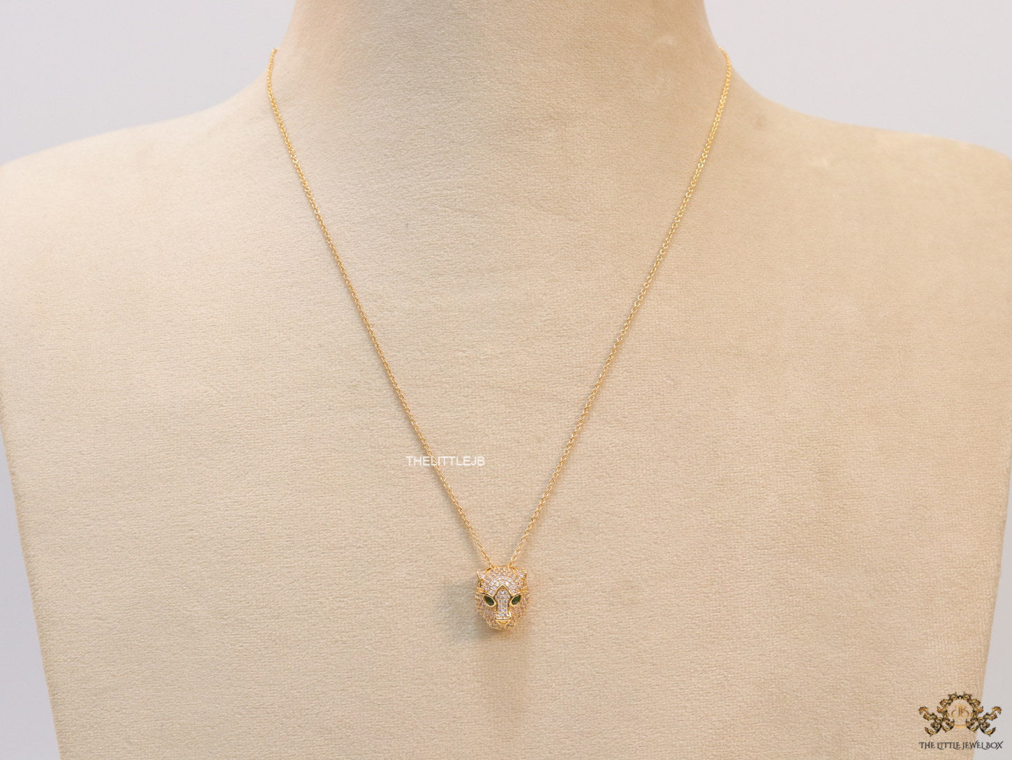 Gold plated cubic zirconia stones panther face motif pendant with emerald green stones details on sleek gold plated chain