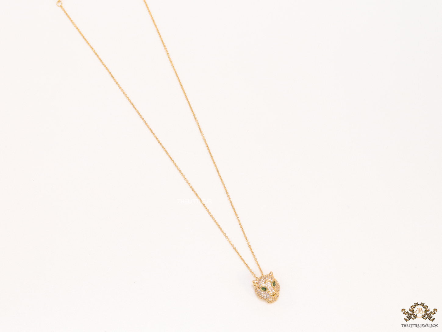 Gold plated cubic zirconia stones panther face motif pendant with emerald green stones details on sleek gold plated chain
