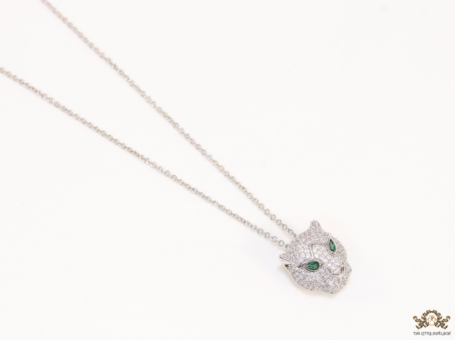 Platinum plated cubic zirconia stones panther face motif pendant with emerald green stones details on sleek Platinum plated chain