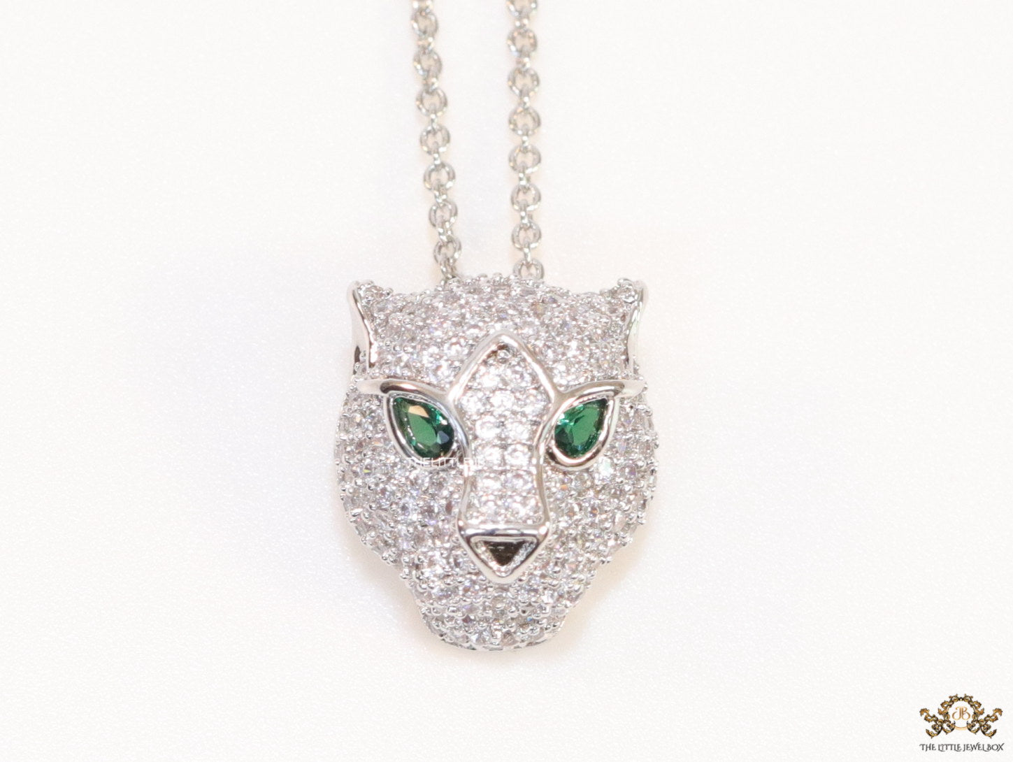 Platinum plated cubic zirconia stones panther face motif pendant with emerald green stones details on sleek Platinum plated chain