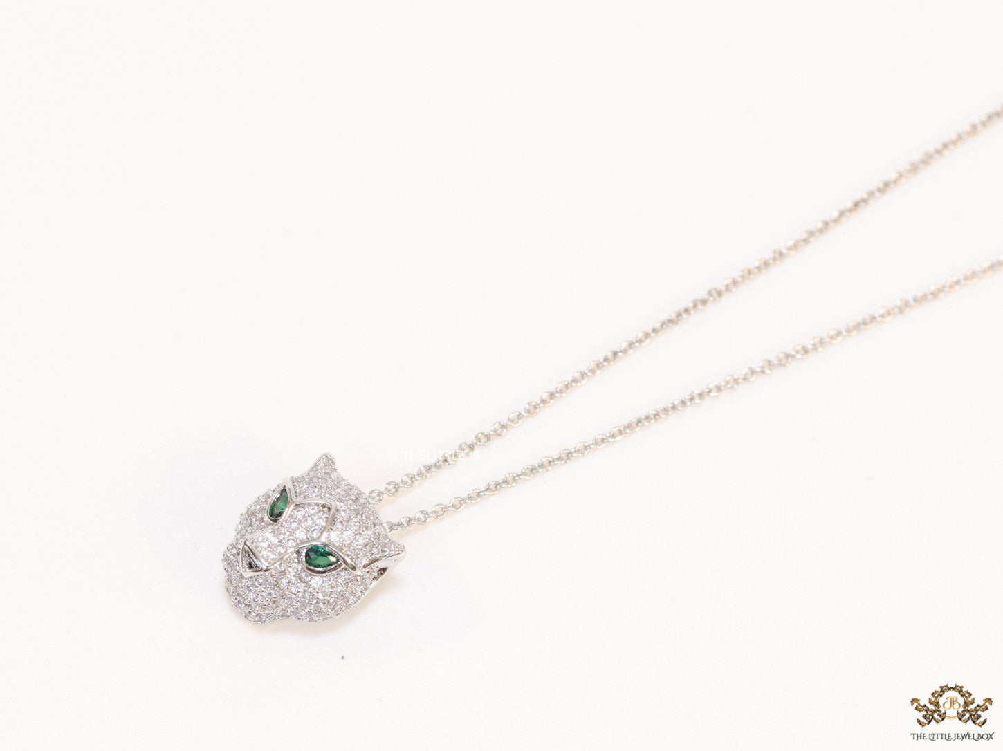 Platinum plated cubic zirconia stones panther face motif pendant with emerald green stones details on sleek Platinum plated chain