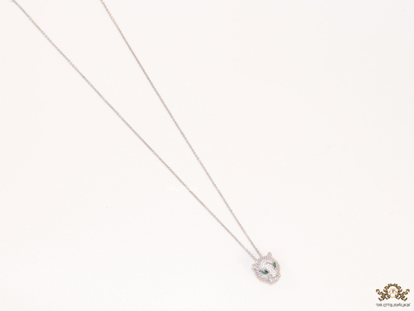Platinum plated cubic zirconia stones panther face motif pendant with emerald green stones details on sleek Platinum plated chain