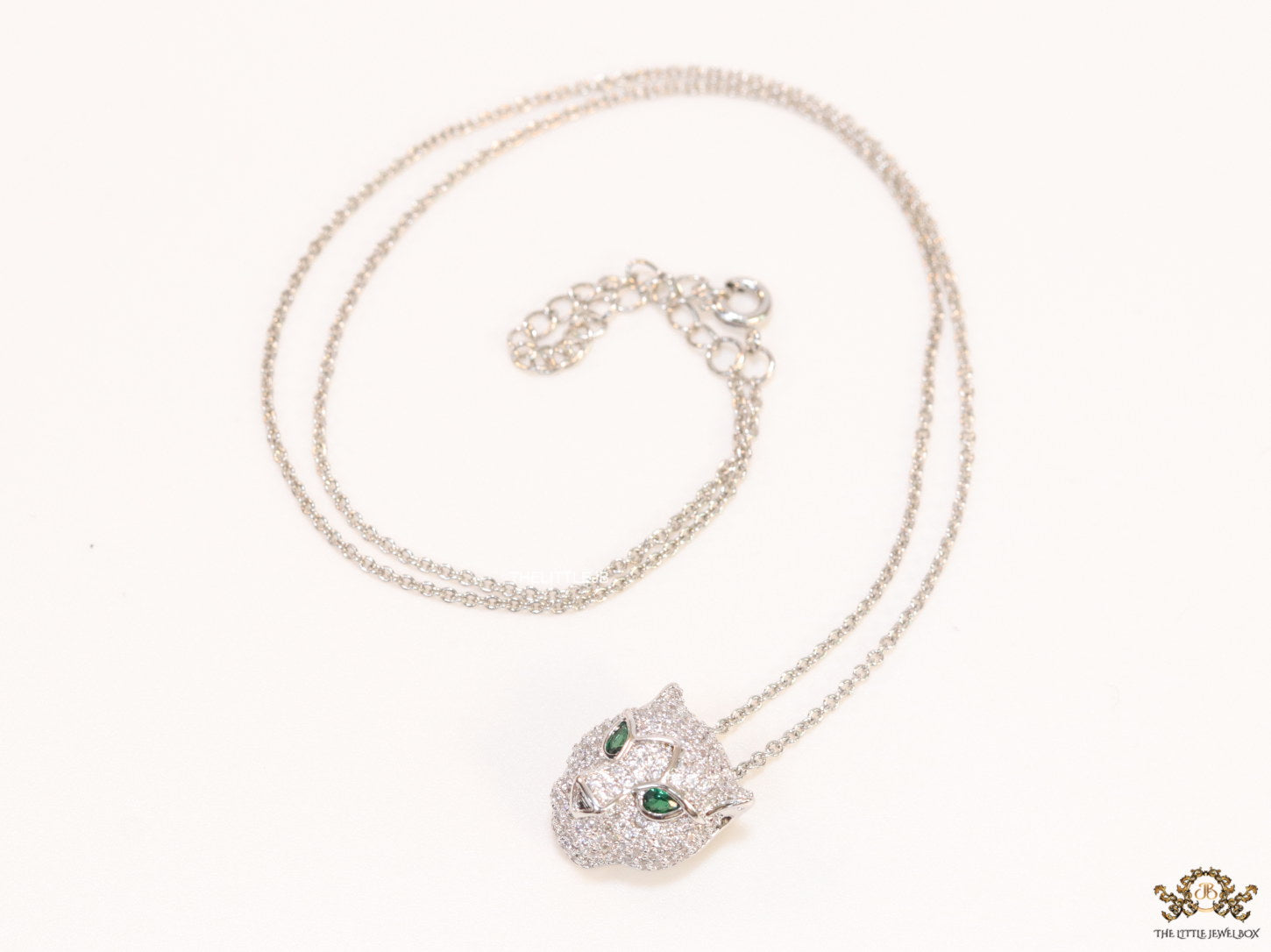 Platinum plated cubic zirconia stones panther face motif pendant with emerald green stones details on sleek Platinum plated chain