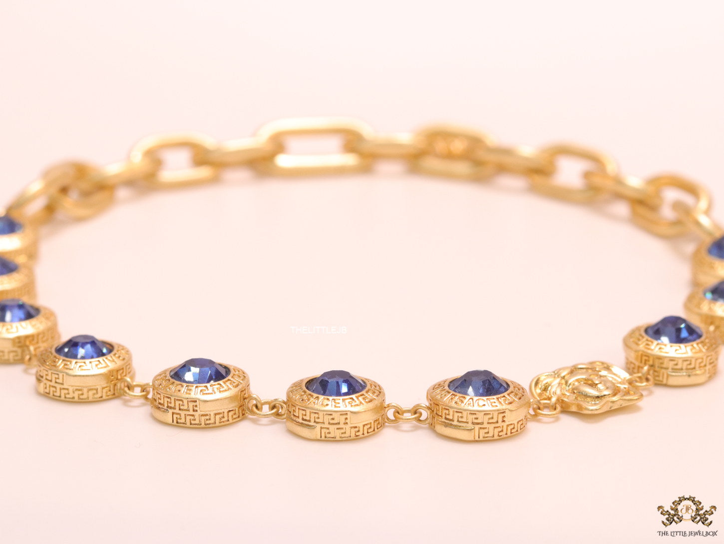 Gold plated link chain with blue cubic zirconia stones and gold plated Medusa motif charm.
