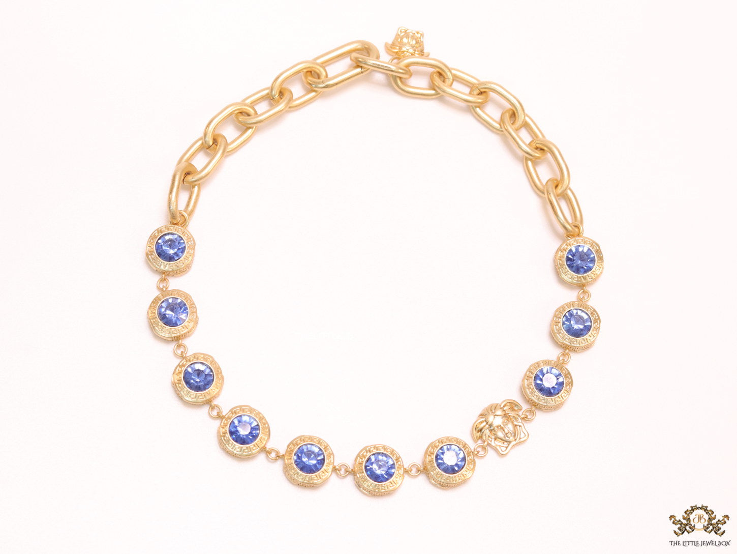 Gold plated link chain with blue cubic zirconia stones and gold plated Medusa motif charm.
