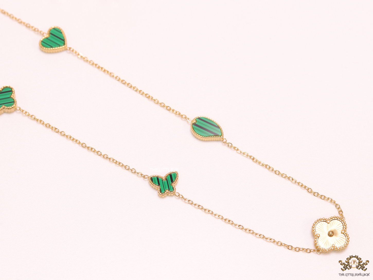 Emerald green clover heart and other shape charms on a sleek long gold plated chain with matching studs
