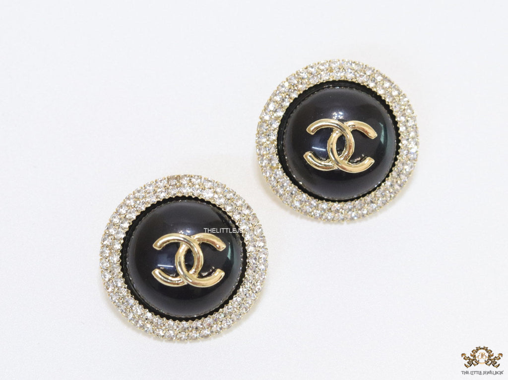 Round black stud earrings with golden twin C motifs lined with cz