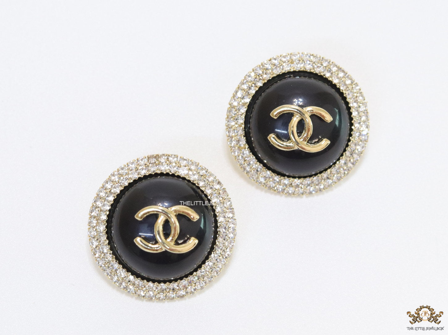 Round black stud earrings with golden twin C motifs lined with cz