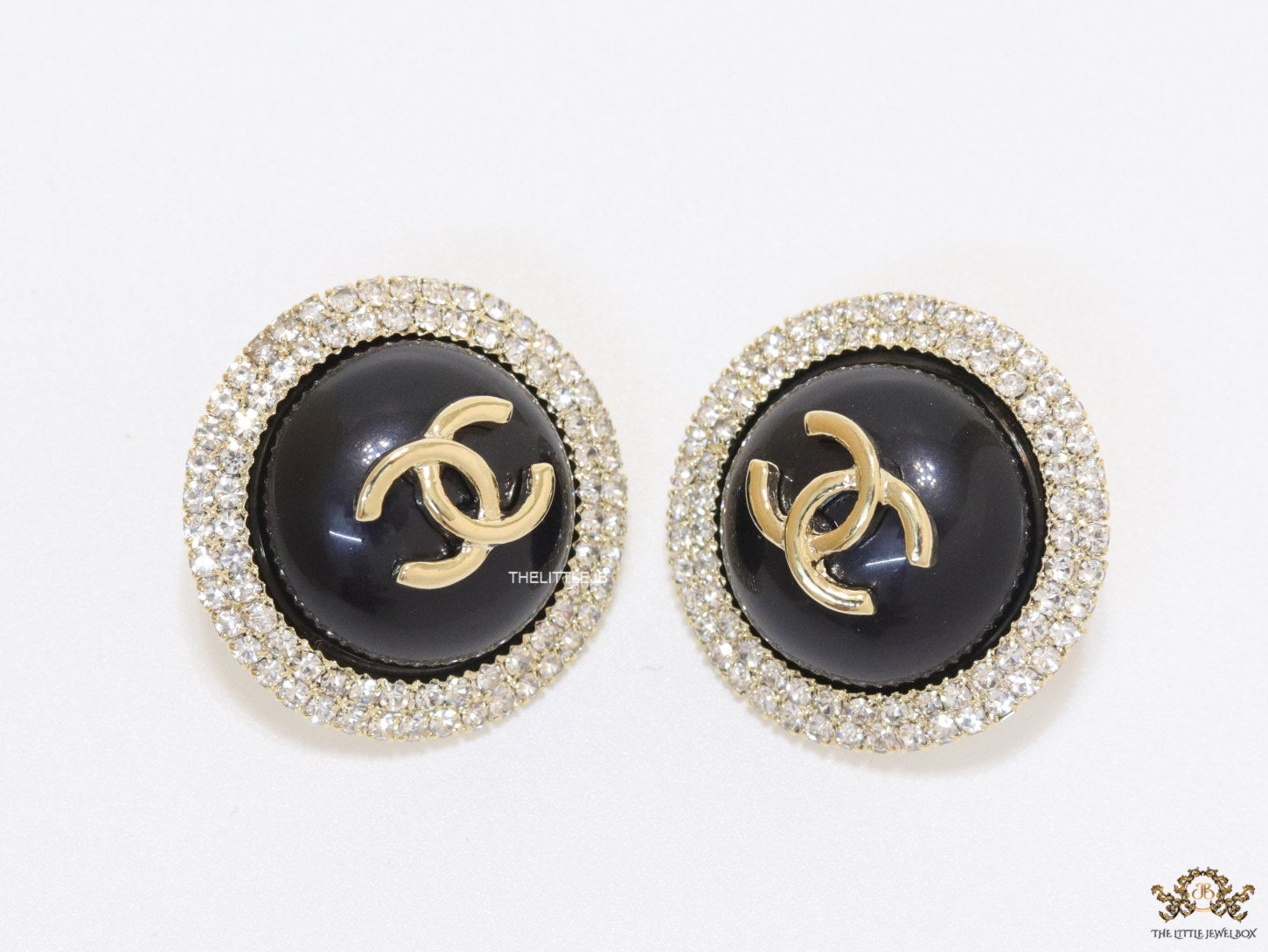 Round black stud earrings with golden twin C motifs lined with cz