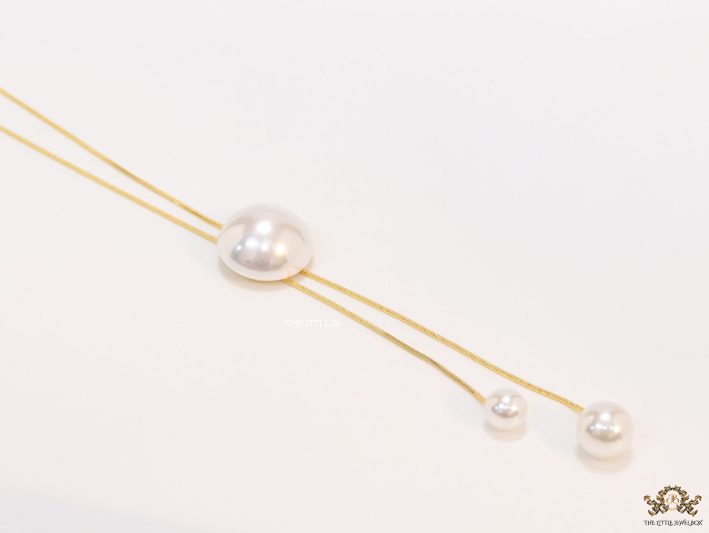 Sleek gold plated chain with different sized shell pearls.