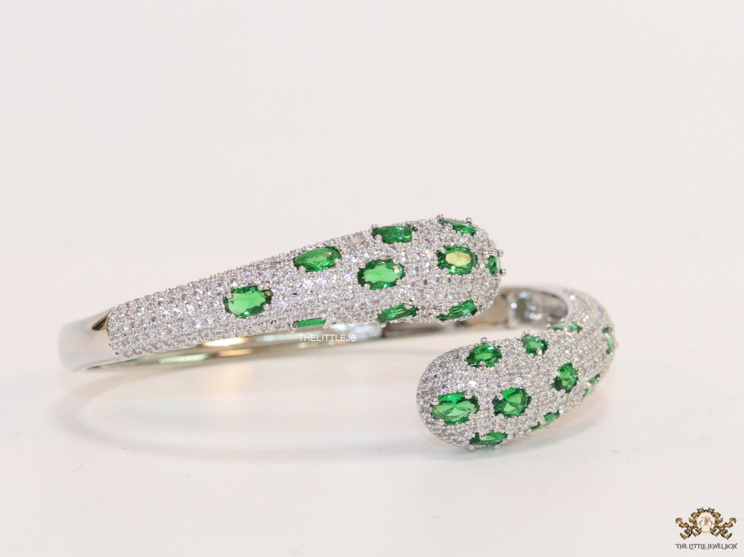 Platinum plated open cz bracelet with emerald green stones